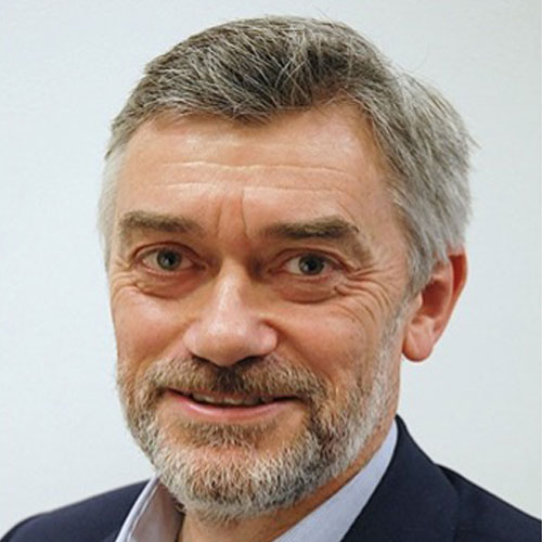 A headshot photograph of Keith Richards, chair of the ncat board, bearded, smiling and wearing a suit