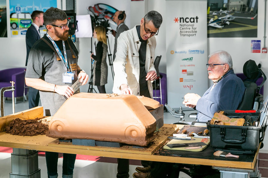 three people surrounding a table with a clay display at a transport event at Coventry University