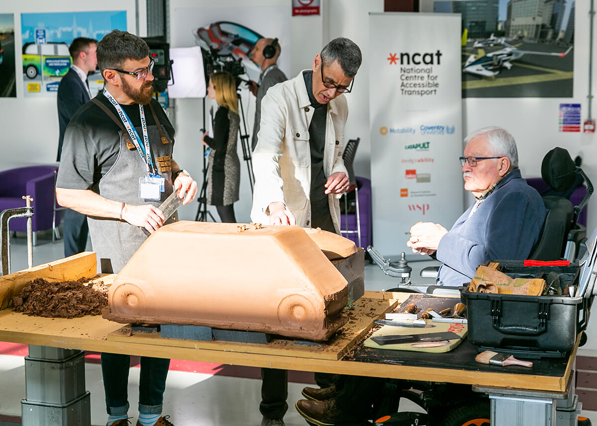 three people surrounding a table with a clay display at a transport event at Coventry University