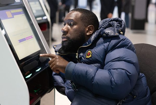 male wheelchair user is pressing buttons on a ticket screen at Heathrow airport