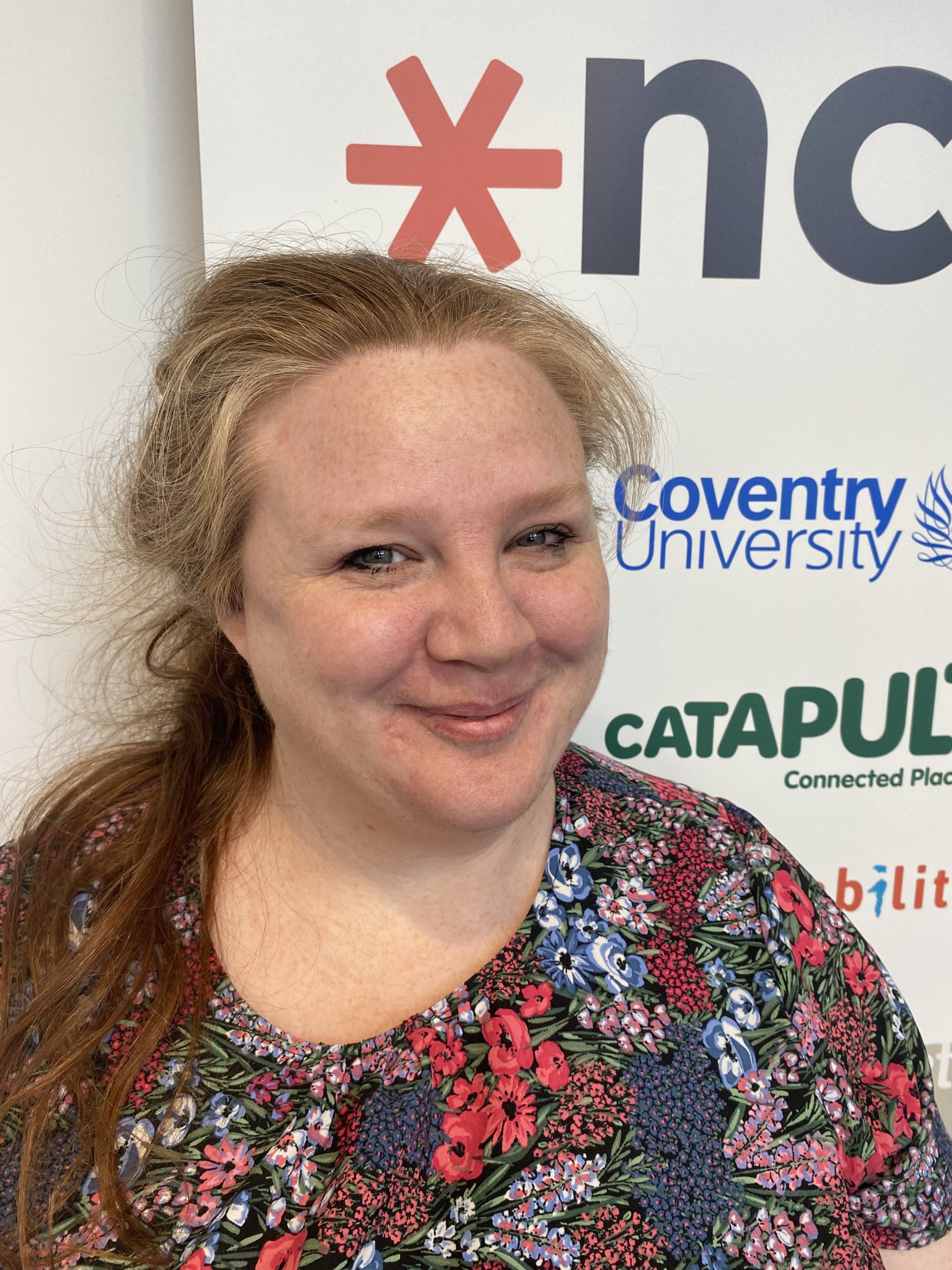 Maddy Hughes headshot in front of ncat poster with Coventry University, Connected Places Catapult and ncat logos slightly obscured.