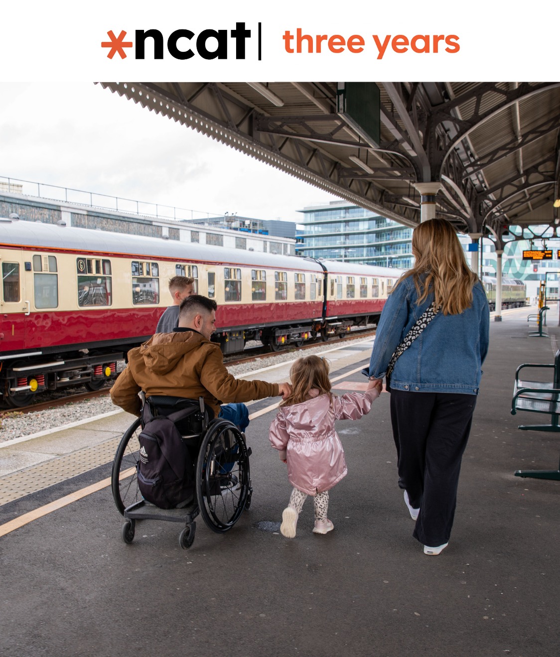 A family walks along a railway station platform. An adult wheelchair user moves alongside a woman and a young child holding hands, with a train stopped beside them on a train platform. The ncat logo and “three years” branding appear on the top of the image.