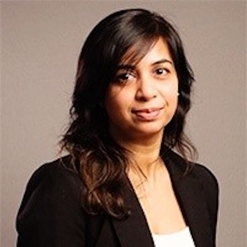a photo headshot of a woman with long brown hair, turned towards the camera and smiling, wearing a white shirt and black jacket