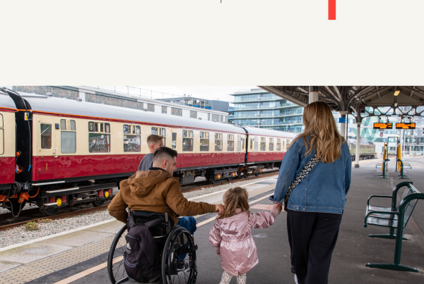 A family walks along a railway station platform. An adult wheelchair user moves alongside a woman and a young child holding hands, with a train stopped beside them on a train platform. The ncat logo and WSP logo branding appear on the top of the image.