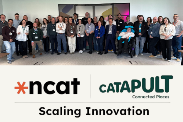 an image combining the logos of the National Centre for Accessible Transport, which is black initials on a white background, sat alongside an orange wheel shape, as well as the words Connected Places Catapult in green, sat above the words Scaling Innovation. Below it is a group picture of 34 people standing or sitting in front of a wall with a window behind all facing the camera and smiling