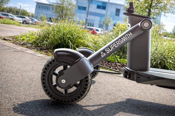 A photo showing the front two wheels of the 3Scooter - showing the Supersmith logo on one arm, in front of grass